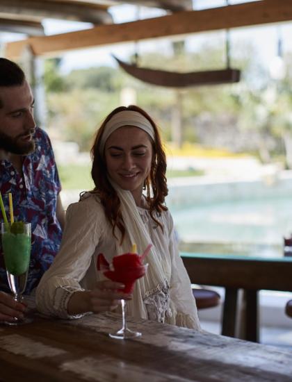 Happy couple enjoying colorful cocktails at an outdoor summer bar.
