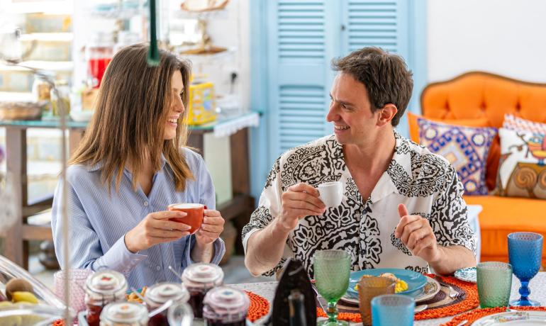 Deux personnes souriantes buvant du café à une table colorée.